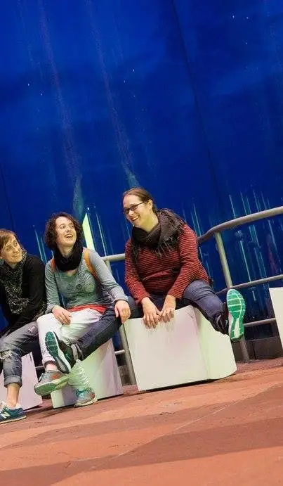 Tres Bouba sentadas nun bloque branco, diante dun telón azul