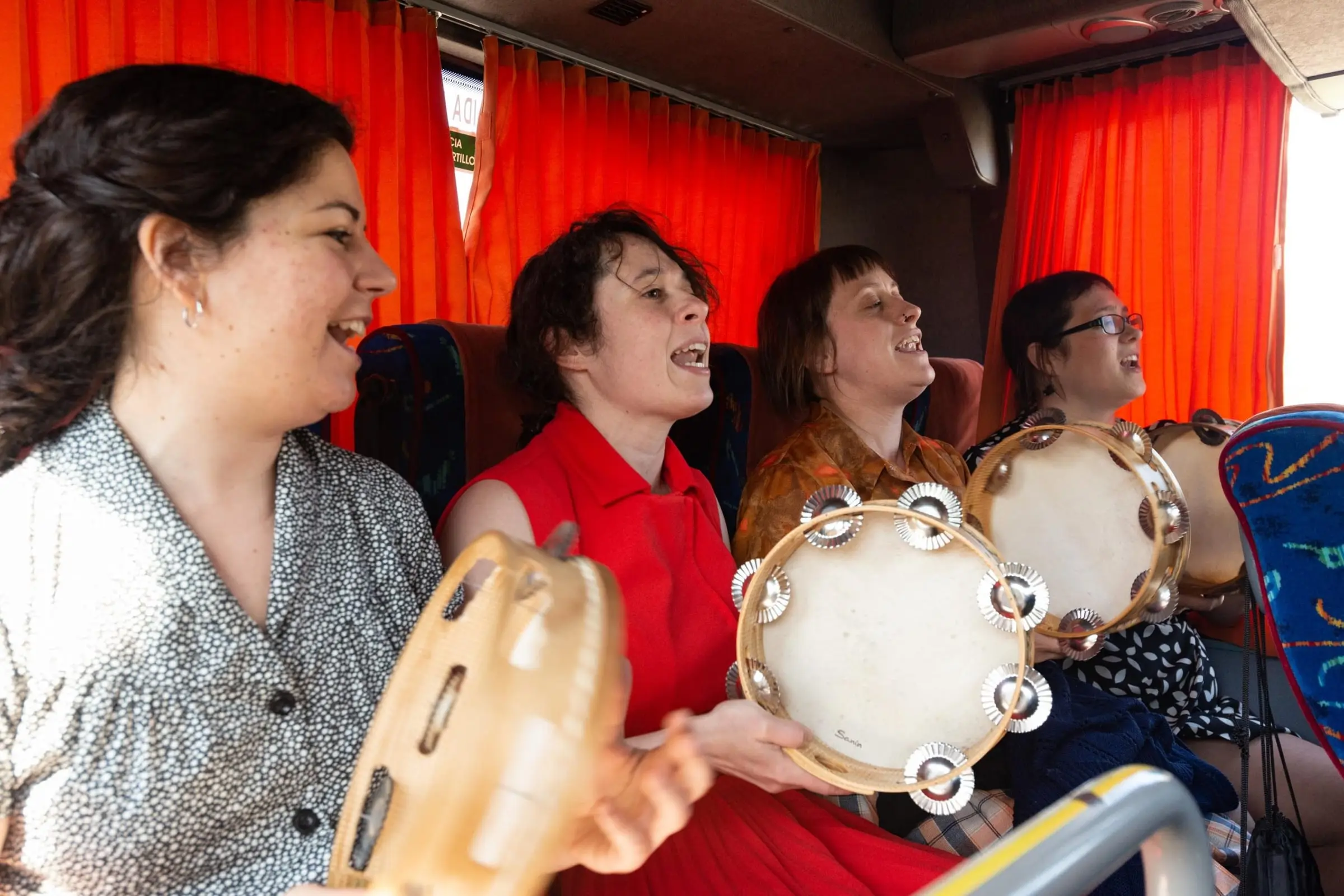 Catro pandeireteiras cantan nun autobús de cortinas laranxas