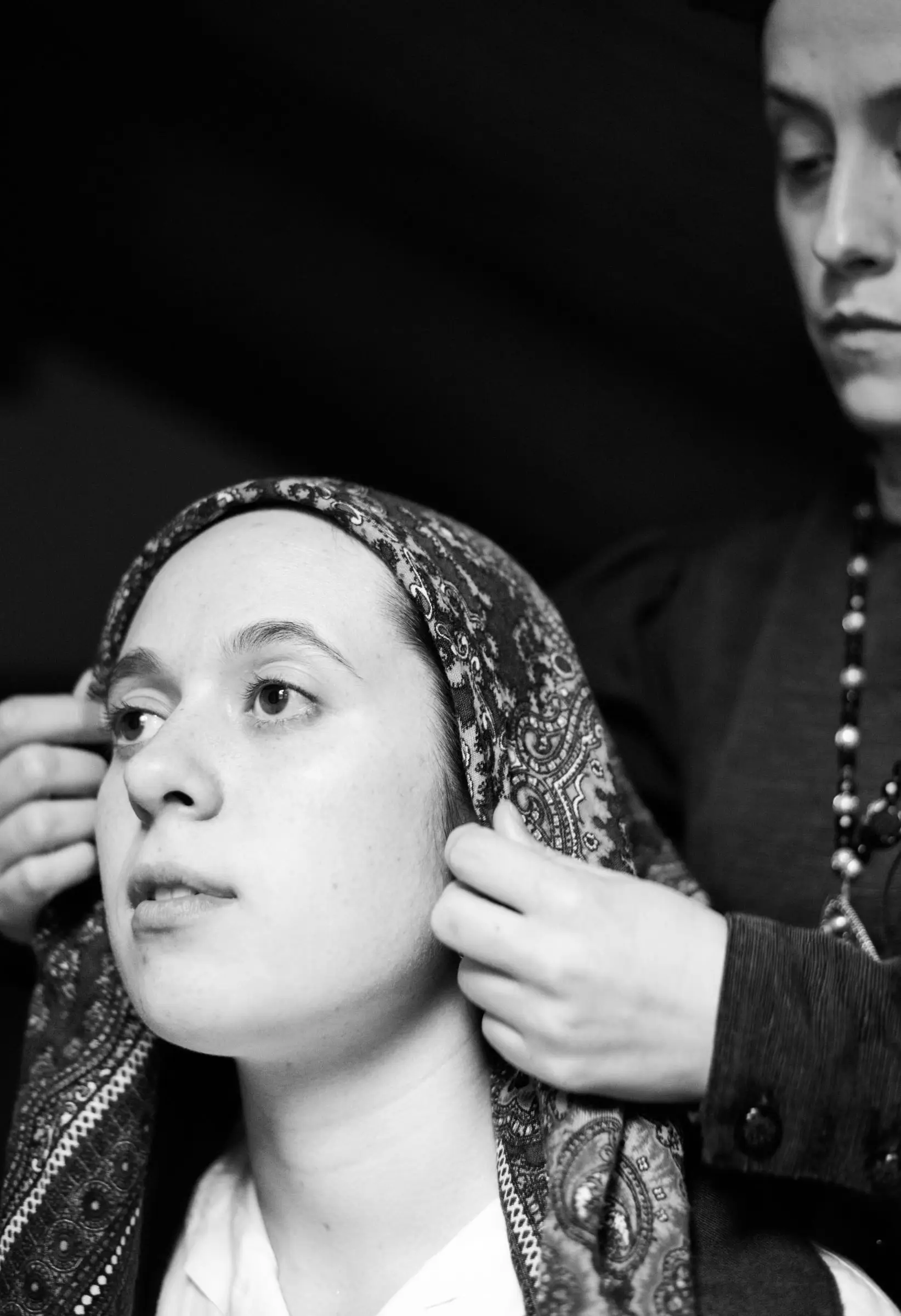 Retrato en branco e negro: unhas mans colócanlle o pano na cabeza a unha moza