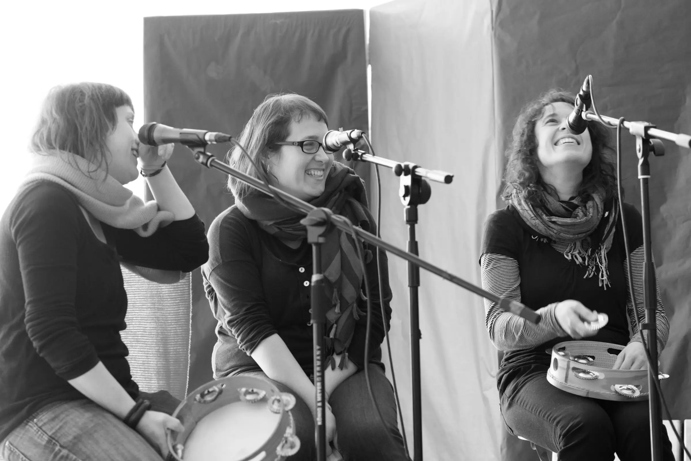 Tres pandeireteiras cantan ao micrófono, en branco e negro